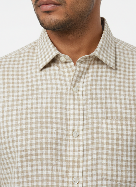Man wearing a beige and white checkered shirt with a neutral background