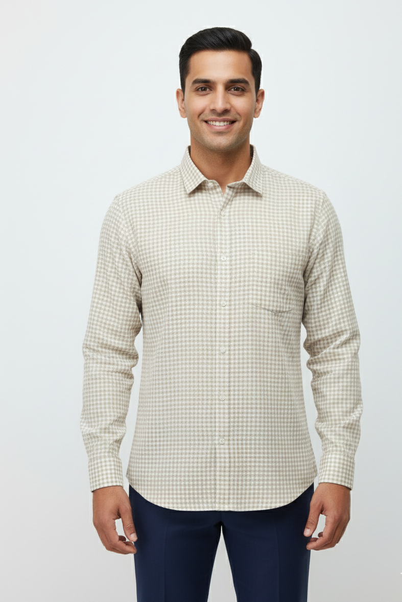 Man wearing a checkered shirt and dark pants against a light background